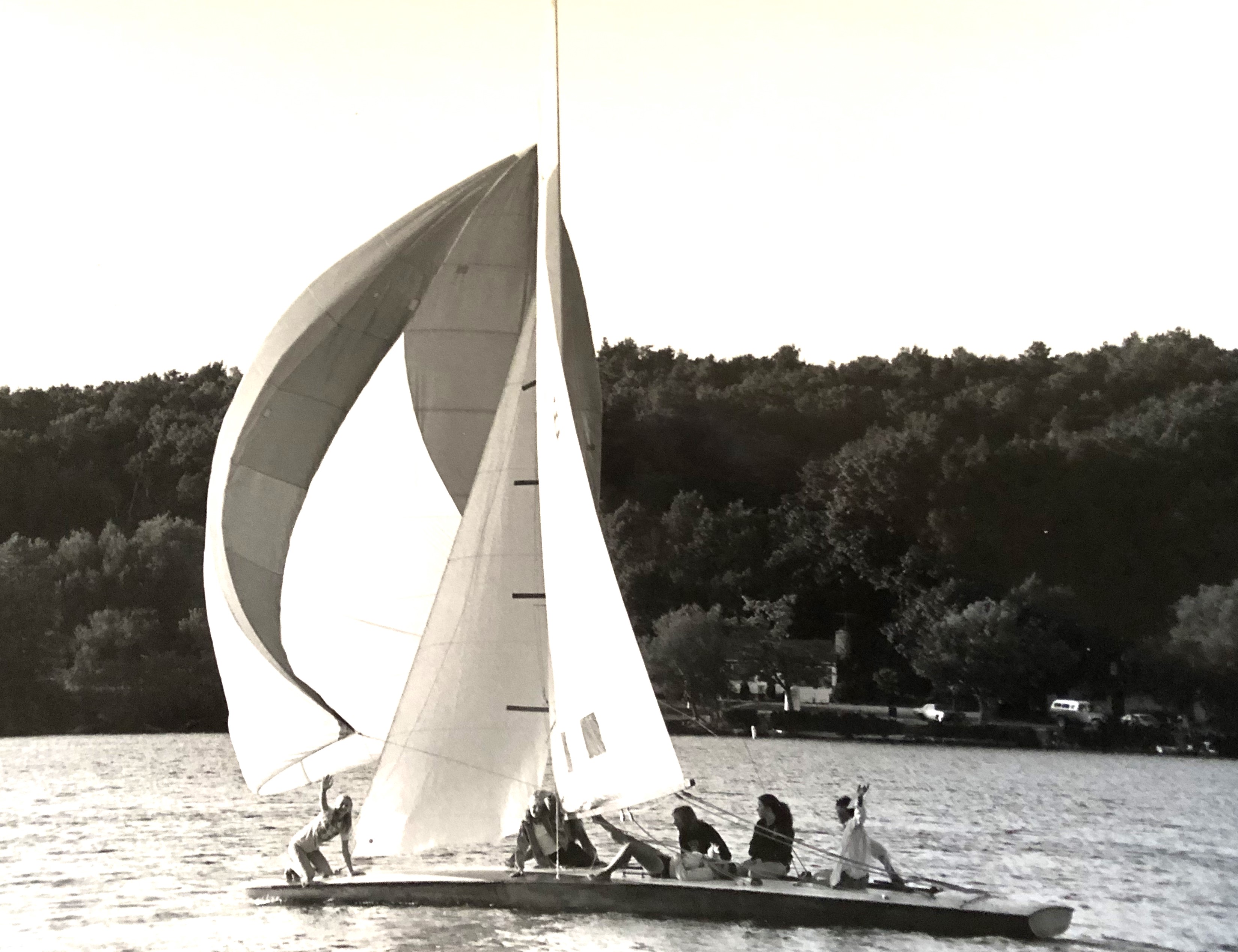 Vintage photo of a large sailboat with four people onboard on the water